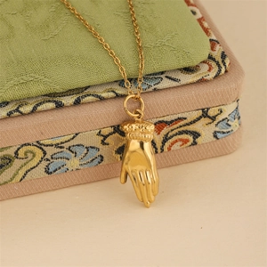 Elegant gold hand pendant necklace with intricate engraved details on a classic link chain