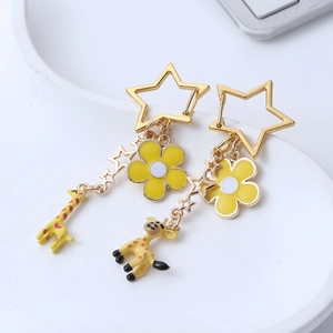 Cute cartoon giraffe earrings with golden star hoops and yellow floral charms on white tray