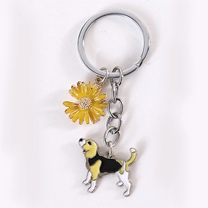 Detail of metal keychain featuring a beagle dog charm and a yellow sunflower pendant