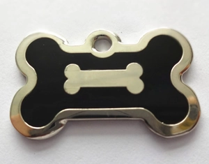 Close-up of black bone-shaped pet ID tag with enamel finish and silver bone pattern