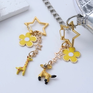 Detailed macro view of yellow cartoon giraffe keychains with star charms and flower pendants