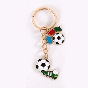 Detalle de llavero de fútbol con bota verde y banderas de colores en oro