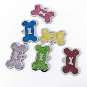Flat lay of colorful bone-shaped pet ID tags with glitter finish and metallic borders
