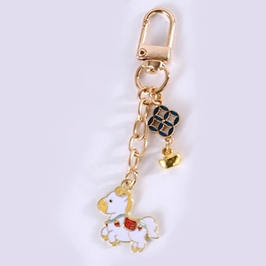 Detail view of zodiac horse keychain with gold metal base and white enamel finish