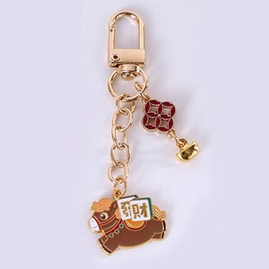 Detail of running horse keychain with lucky coin and floral charms in gold finish