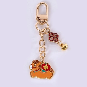 Detail of golden zodiac horse keychain with red apple charm and lucky fushi symbol