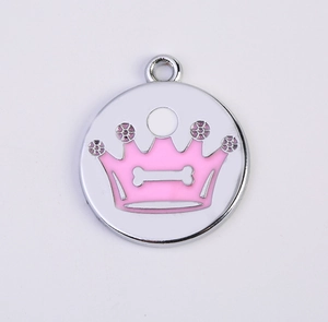 Macro detail of round metal pet ID tag with pink crown pattern and bone logo design