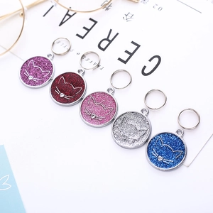 Detailed view of colorful glitter cat face ID tags with metallic rings and shiny finish