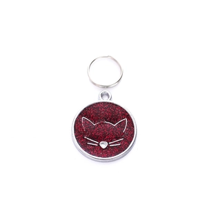 Detailed view of red glitter pet ID tag with a cute white cat face design and silver ring