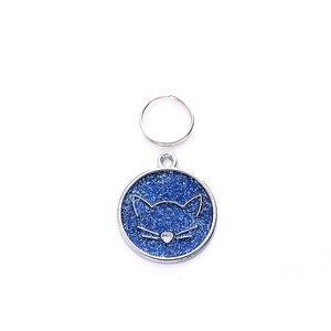 Detailed view of round zinc alloy pet tag with blue glitter and silver cat face design