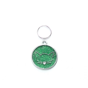 Detail of round green glitter pet ID tag with cat face design and silver keyring