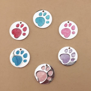 Detail view of round metal pet ID tags with colorful glitter paw prints and polished finish