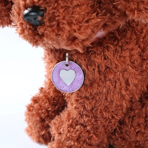 Detail of a purple glitter dog tag with silver heart inlay on a pet collar accessory