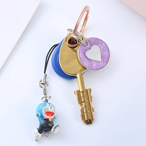 Detailed view of 3D Doraemon pendant and blue round tag on a gold keychain set