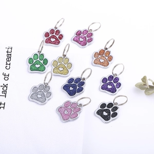 Macro detail of paw-shaped pet ID tags with glitter finish and heart cutout design