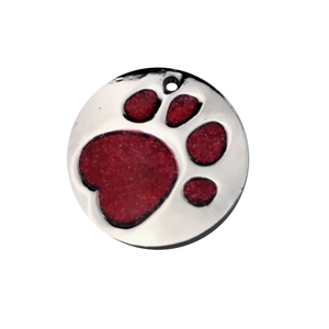 Detail of round dog tag with red glitter paw print and polished silver metal surface