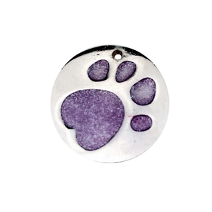 Close-up of a round silver metal pet tag with a purple glittery paw print design