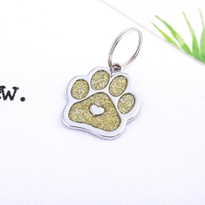 Glittering paw-shaped pet ID tag with heart detail and metal ring in gold finish