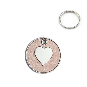 Close-up of a pink glitter round pet ID tag with a polished silver heart and metal ring