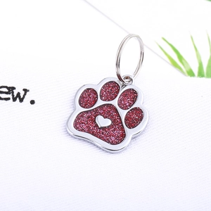 Macro detail of paw-shaped pet tag with red glitter finish and small heart design