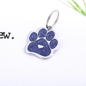 Detailed view of paw-shaped pet ID tag with blue glitter and heart cutout in silver frame