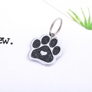 Glittery paw-shaped pet ID tag with heart detail and metal ring on white background