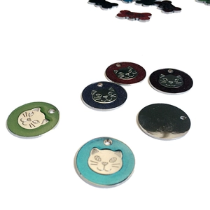 Close-up of colorful metal pet ID tags with embossed cat face designs for collars