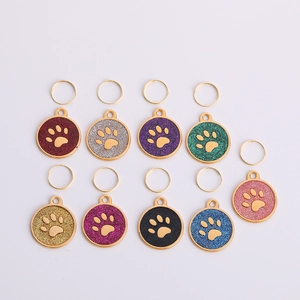Detail view of round glitter paw print pet ID tags in nine vibrant colors with gold frames