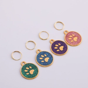 Detailed view of colorful glitter paw print pet ID tags with shiny gold metal edges