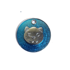 Detail of round cat pendant with golden metal feline relief and sparkling blue glitter