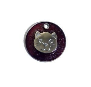 Macro detail of round pet ID tag with dark red glitter and silver cat head motif