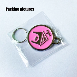 Detailed view of pink zinc alloy dog ID tag with enamel design in clear packaging