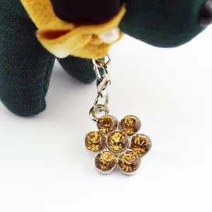 Macro view of flower-shaped pet charm with amber crystals and silver lobster clasp