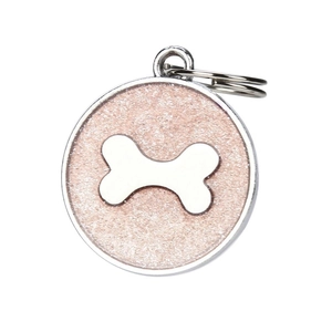 Macro detail of round pink glitter pet ID tag with a white bone symbol on white background