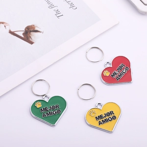 Three colorful heart-shaped pet ID tags with MEJOR AMIGO lettering and paw prints
