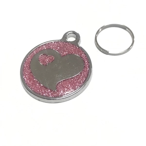 Dettaglio di una medaglietta rotonda per animali in argento con glitter rosa e cuore
