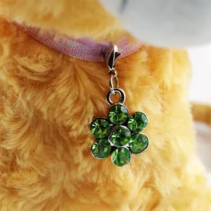 Detailed close-up of a green crystal flower pet collar charm with a metal lobster clasp