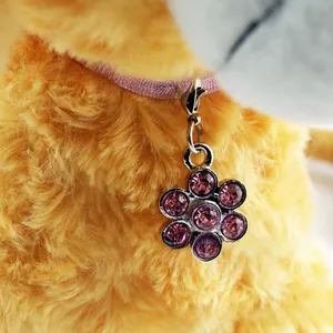 Detail of flower shaped pet charm with purple rhinestones on a pink ribbon strap