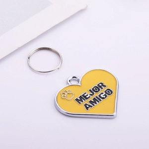 Detail of heart-shaped yellow enamel pet tag with Mejor Amigo text and paw print