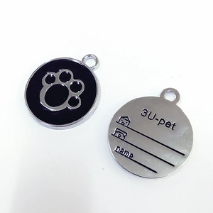 Detail of round zinc alloy pet tag featuring black enamel paw print and engraved back