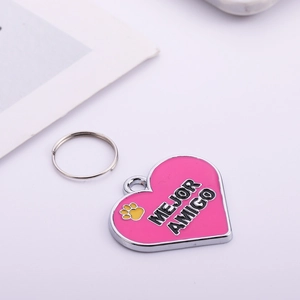 Detailed close-up of a pink heart-shaped pet ID tag with engraved Mejor Amigo lettering