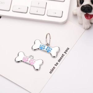 Close-up of bone-shaped zinc alloy pet ID tags with pink and blue paw prints