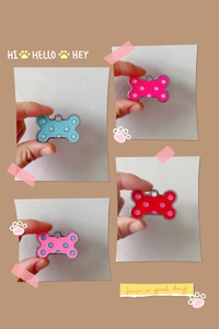 Dettaglio di medagliette a forma di osso in blu, rosa e rosso con motivi a pois carini
