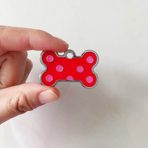 Dettaglio della targhetta per cani a forma di osso rosso con pois rosa e bordo argento