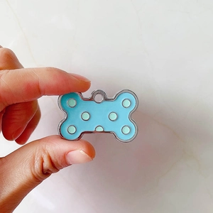 Dettaglio della piastrina per cani a forma di osso in smalto blu a pois verdi