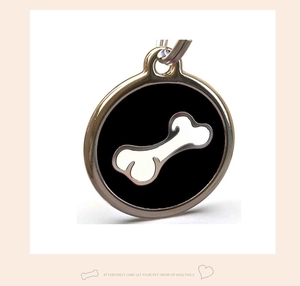 Detail showing a round pet ID tag with black enamel and a white bone pattern in macro view