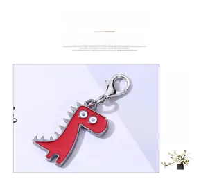 Detail of red cartoon dinosaur pendant with silver metal edge and lobster clasp