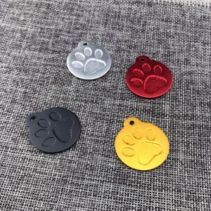 Detail view of round aluminum pet tags with embossed paw prints in four metallic colors