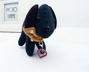 Detail of green plush dog charm with yellow knit scarf and red rhinestone heart pendant