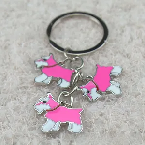 Detailopname van drie roze Terrier-bedeltjes aan een zilveren metalen sleutelhanger